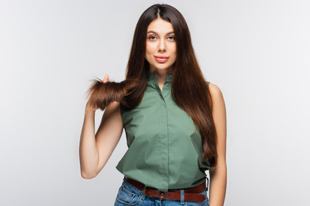 young woman showing healthy hair ends isolated on grayの写真素材