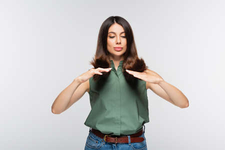 young woman looking at hair ends isolated on grayの写真素材