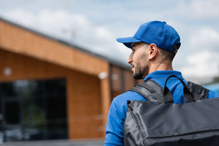 Side view of muslim deliveryman in uniform with thermo backpack outdoorsの写真素材