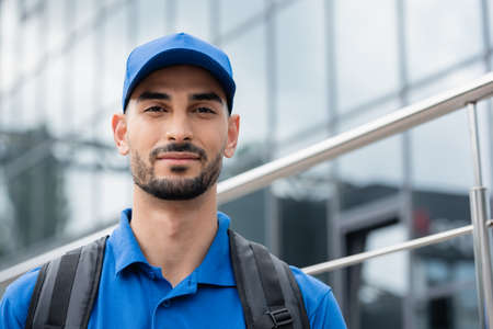 Arabian courier with backpack looking at camera outdoorsの写真素材