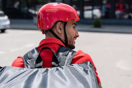 Side view of muslim deliveryman in helmet and thermo backpack outdoorsの写真素材