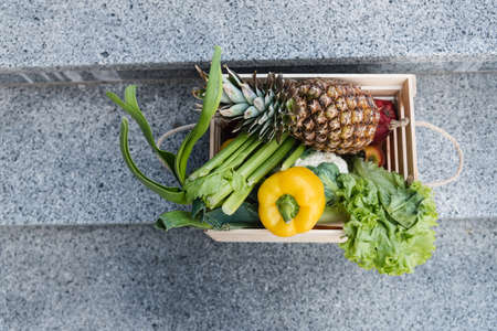 Top view of fresh fruits and vegetables in wooden box on stairsの写真素材