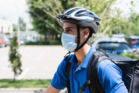 Muslim deliveryman in safety helmet and medical mask outdoorsの写真素材
