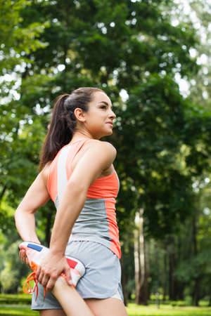 brunette sportswoman warming up in park