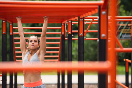 athletic woman exercising on blurred horizontal ladder outside