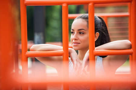 smiling sportswoman looking away near orange vertical ladder outsideの写真素材