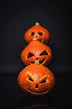 row of creepy and carved pumpkins on blackの写真素材