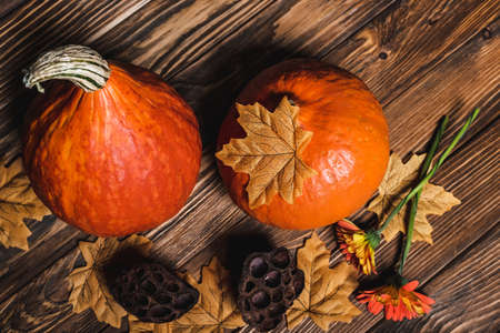 top view of flowers and autumnal leaves near orange pumpkins and dried lotus pods on wooden surfaceの写真素材