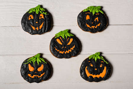 flay lay with black and spooky pumpkin shape halloween cookies on white surfaceの写真素材