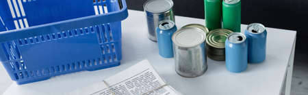 Tin cans, newspapers near basket on table, bannerの写真素材