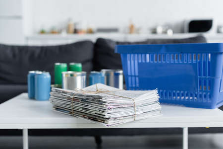 Newspapers near blurred tin cans and basket on table at homeの写真素材