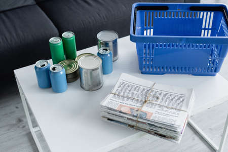 High angle view of newspapers, tin cans and basket on tableの写真素材
