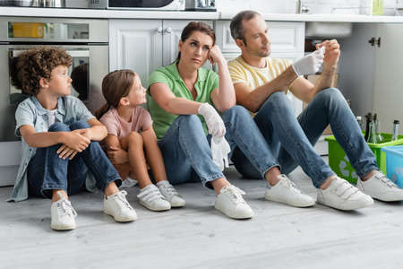 Exhausted family with kids sitting near boxes with recycle sign in kitchenの写真素材