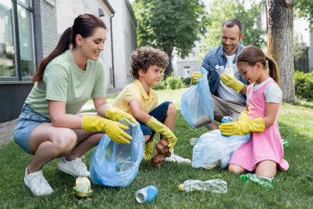 Positive woman in rubber gloves collecting trash in bags outdoorsの写真素材