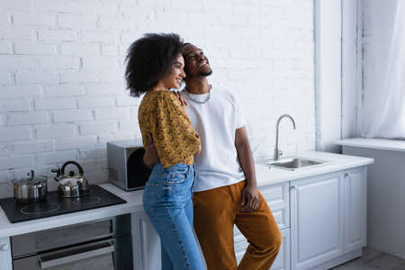 Positive african american couple standing in kitchenの写真素材