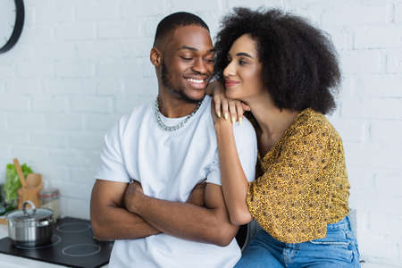 Young african american woman hugging smiling boyfriend at homeの写真素材