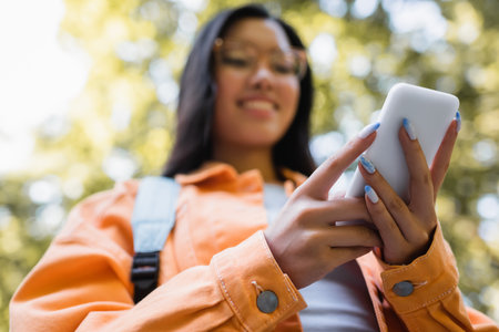 low angle view of blurred asian woman using mobile phone outdoors