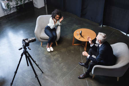 high angle view of african american journalist talking with guest in interview studioの写真素材
