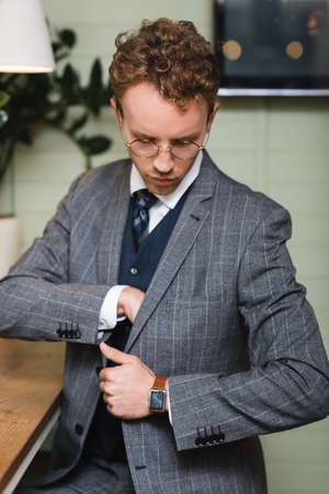 confident businessman in formal wear looking at inside pocket of blazer
