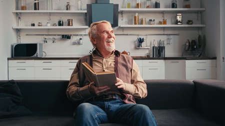 happy senior man holding book at homeの写真素材