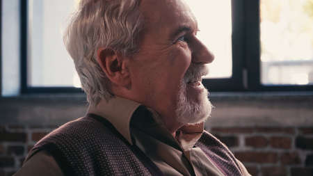 side view of cheerful retired man smiling at homeの写真素材