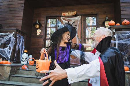 excited father and daughter in halloween costumes near house with decoration