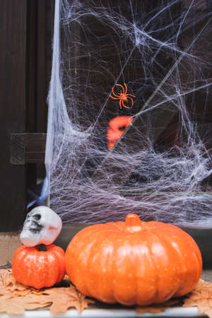 orange pumpkins and spooky skull on porch decorated with spider netの写真素材