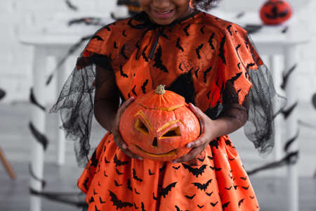 cropped view of smiling african american kid holding carved pumpkinの写真素材