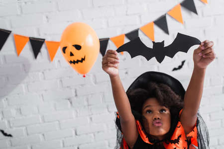 african american girl in halloween costume holding paper cut batの写真素材