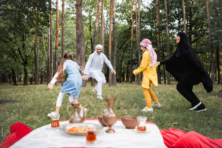 Happy muslim family playing near food in park