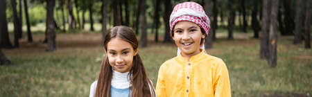 Smiling muslim kids looking at camera in park, bannerの写真素材