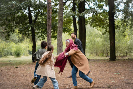 Muslim mother playing with daughter near family in parkの写真素材