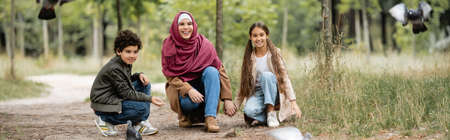 Muslim family looking at blurred birds in park, bannerの写真素材
