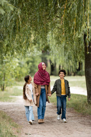 Arabian family walking under willow tree in parkの写真素材