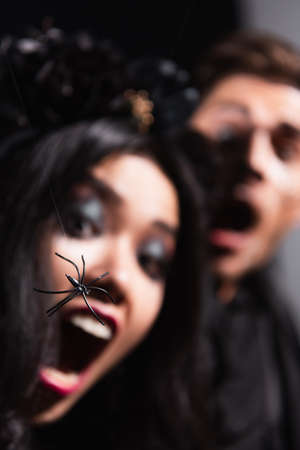 close up view of toy spider near blurred interracial couple screaming from fearの写真素材