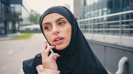 Young arabic woman in hijab having phone call outside