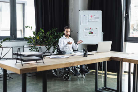 disabled businessman pointing with hands during video conference on laptop in office
