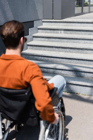 blurred man in wheelchair near stairs in cityの写真素材