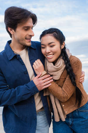 Positive multiethnic couple hugging outdoors during weekendの写真素材