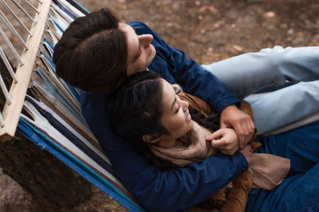 Overhead view of happy interracial couple hugging in hammock outdoorsの写真素材