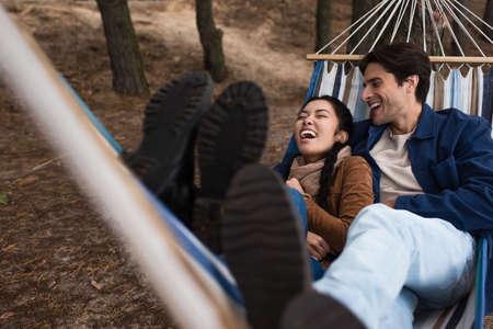 Asian woman laughing near boyfriend in hammock outdoorsの写真素材