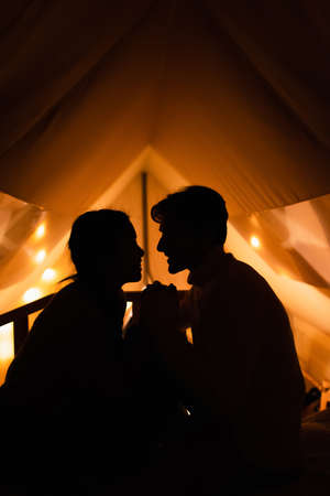 Side view of silhouettes of couple in glamping house in nightの写真素材