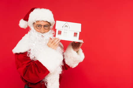 Santa claus holding house model isolated on redの写真素材