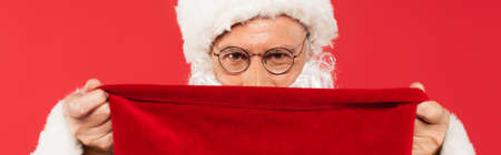 Santa claus covering face with sack isolated on red, bannerの写真素材