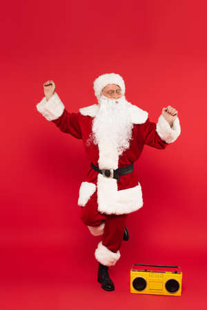 Santa claus dancing near boombox on red backgroundの写真素材