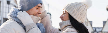 happy woman adjusting hat of boyfriend outside, bannerの写真素材