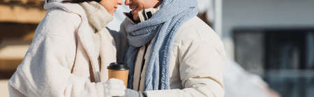cropped view of happy young man holding paper cup near cheerful girlfriend, bannerの写真素材