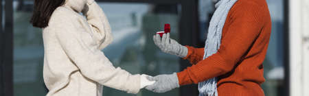 cropped of man holding box with wedding ring near young woman in wintertime, bannerの写真素材