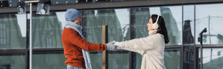 young woman in ear muffs holding hands with boyfriend outside, banner