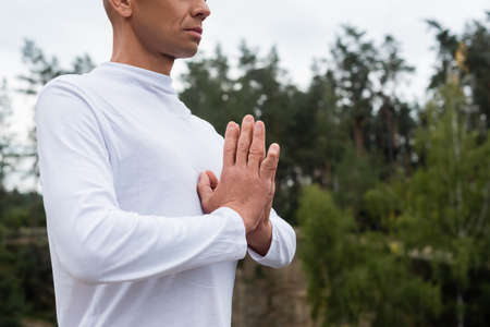 cropped view of buddhist in white sweatshirt meditating with praying handsの写真素材